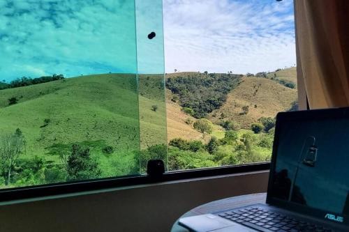 a laptop computer sitting on a table in front of a window at Recanto dos Beija Flores, Chalé lantana a in Monte Alegre do Sul