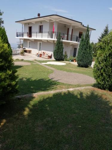 a large white house with a large yard with trees at Bujtinat Peci in Elbasan