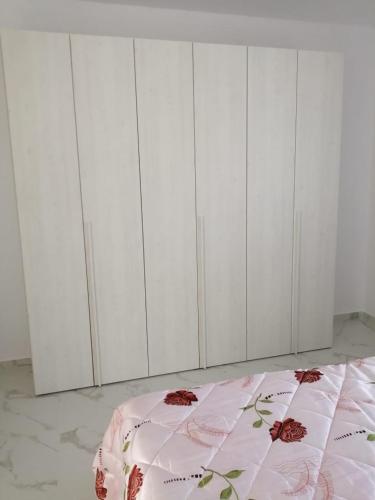 a white bedroom with a bed with a pink blanket at Bujtinat Peci in Elbasan