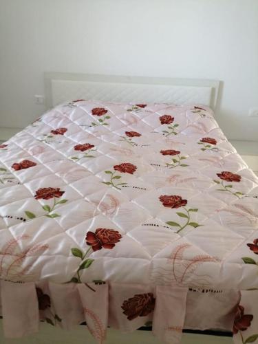 a bed with a white blanket with flowers on it at Bujtinat Peci in Elbasan