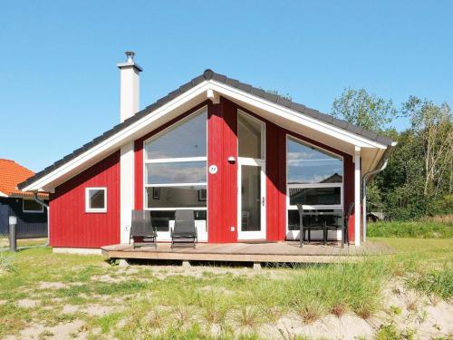 ein rotes Haus mit einer Terrasse mit zwei Stühlen in der Unterkunft 6 person holiday home in Gro enbrode in Großenbrode