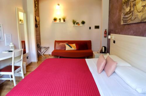 オージオ・ソットにあるMi Casa Affittacamereのベッドルーム1室(ピンクの枕とソファ付きのベッド1台付)