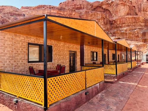 Un edificio con una terraza con sillas. en wadi rum bedouin stars camp, en Wadi Rum