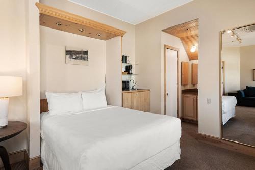 1 dormitorio con cama blanca y espejo en Independence Square 300, Nice Hotel Room with Great Views, Location & Rooftop Hot Tub! en Aspen