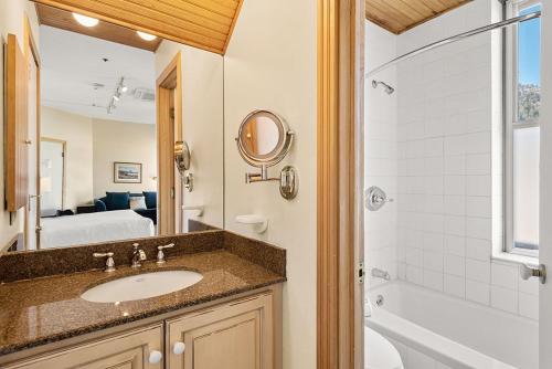 a bathroom with a sink and a mirror and a tub at Independence Square 300, Nice Hotel Room with Great Views, Location & Rooftop Hot Tub! in Aspen