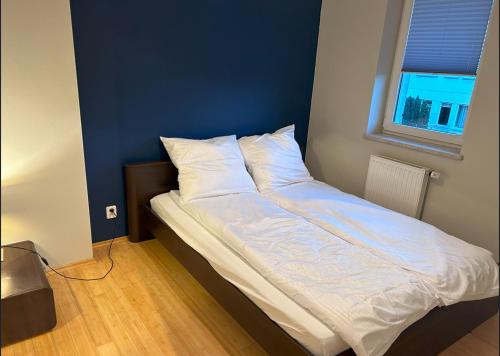 Una cama con sábanas blancas y almohadas en un dormitorio en Apartament w Wesołej, en Varsovia