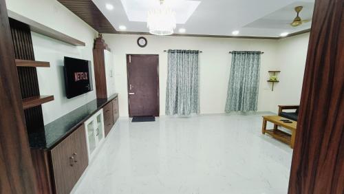 a room with a hallway with a door and a tv at TrueLife - Chinmai Nivas - Breakfast Included - Modern 2BHK homes for families - Tirumala Mountain View - Fast WiFi - Many restaurants nearby - Hall, AC bedrooms, Modular Kitchen - Android TV - 250 Jio Channels - Top Service with lots of Love in Tirupati