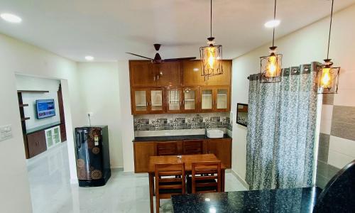 a kitchen with a dining table and a counter top at TrueLife - Chinmai Nivas - Breakfast Included - Modern 2BHK homes for families - Tirumala Mountain View - Fast WiFi - Many restaurants nearby - Hall, AC bedrooms, Modular Kitchen - Android TV - 250 Jio Channels - Top Service with lots of Love in Tirupati