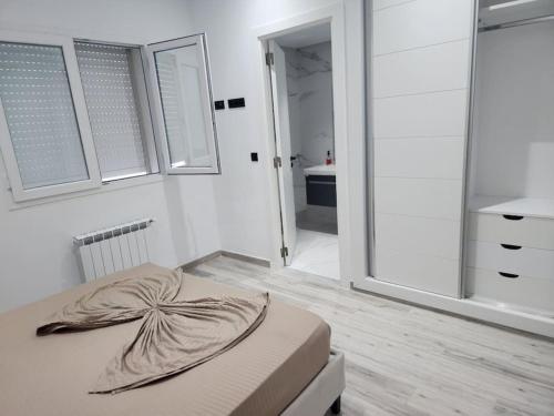 a white room with a bed and a bathroom at Magnifique Appartement au coeur de Monastir in Monastir