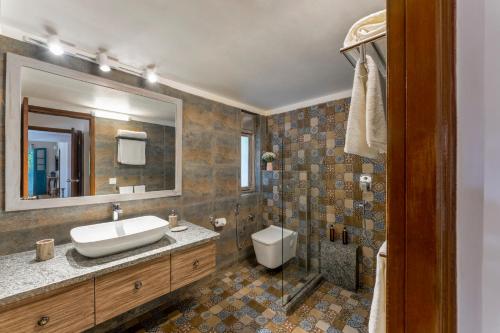a bathroom with a sink and a toilet and a mirror at Beachside Bliss Villas Candolim 10 min walk from Sinquerim Beach in Sinquerim