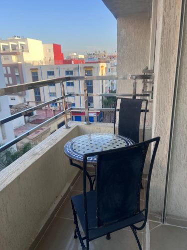 a table and chair on a balcony with a view at Luxury Center Town Apartment in Kenitra