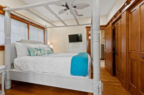 a bedroom with a white bed with a ceiling fan at Flagler Cottage - 1 Block to Historic District in Saint Augustine