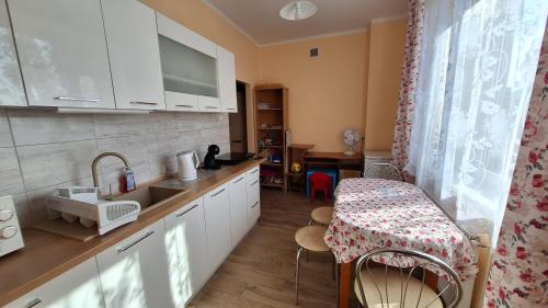 a kitchen with white cabinets and a table and a stool at Mieszkanko na peryferiach in Chrzanów