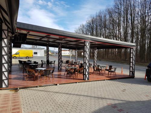 een overdekt terras met tafels en stoelen en een geel busje bij TALIJA in Mrčajevci