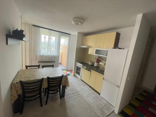 uma cozinha com uma mesa e um frigorífico branco em Apartman Zenica em Zenica