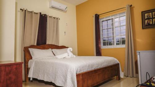 a bedroom with a bed with white sheets and a window at Incognito Reggae Rooms in Kingston