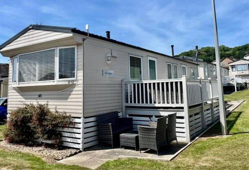 a small house with a porch and two chairs at 8 berth pet friendly caravan, Penrhyn Bay, Llandudno in Llandudno
