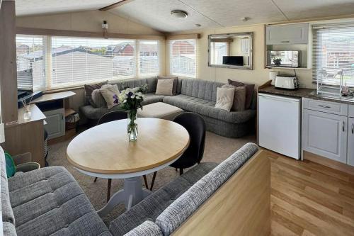 a living room with a couch and a table at 8 berth pet friendly caravan, Penrhyn Bay, Llandudno in Llandudno