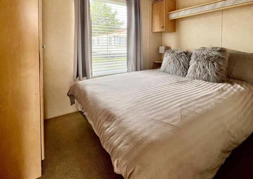 a bedroom with a large white bed with a window at 8 berth pet friendly caravan, Penrhyn Bay, Llandudno in Llandudno