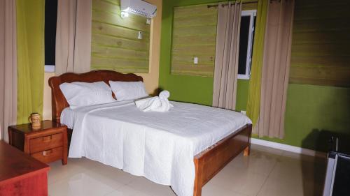 a bedroom with a bed with white sheets and green walls at Incognito Reggae Rooms in Kingston
