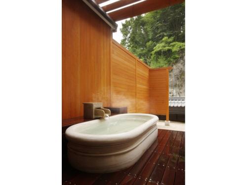 uma banheira na casa de banho com paredes de madeira em Kinugawa Onsen Yusuikiko Hotel Otaki - Vacation STAY 68843v em Nikko