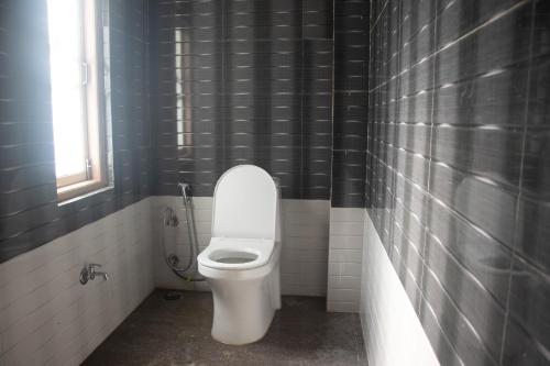 a bathroom with a white toilet and a window at Malabika Homestay in Padamchen