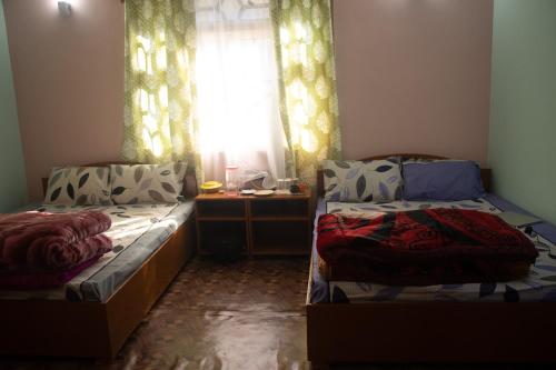 two beds in a room with a window at Malabika Homestay in Padamchen
