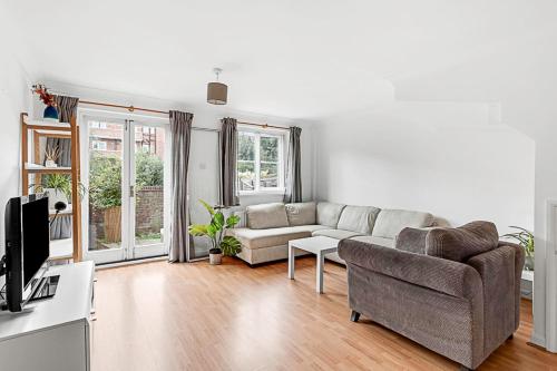 ein Wohnzimmer mit einem Sofa und einem TV in der Unterkunft Beautiful Richmond House in Richmond upon Thames