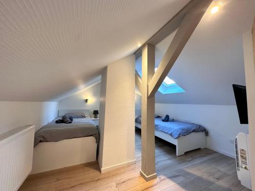 a attic bedroom with two beds and a pole at Le trésor de Khalis in Colmar