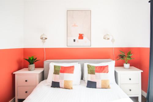 a bedroom with orange walls and a bed with pillows at Beautiful Bath garden flat with stunning views - Mycityhaven in Bath