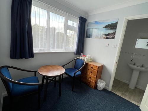 a room with a table and two chairs and a sink at Berry Hotel in Paignton