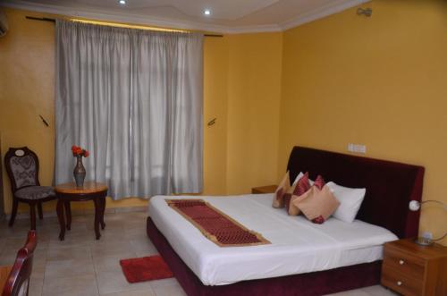 Schlafzimmer mit einem großen weißen Bett und einem Fenster in der Unterkunft Hollandas Hotel in Ijebu Ode