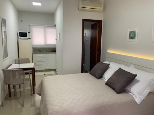 1 dormitorio con cama, mesa y cocina en Pousada Mar de Cristal en Florianópolis