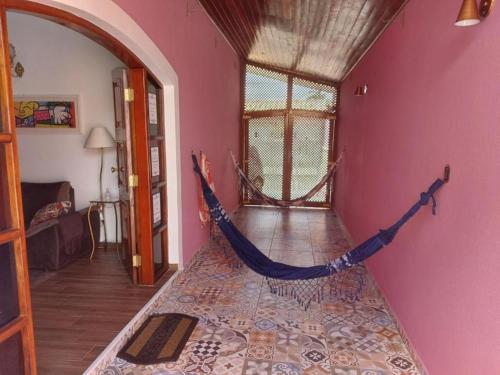 a room with a hammock in a room at Casa Rosa de Peruíbe - Casa de Temporada 3 dormitórios, 10 hóspedes, piscina, wi-fi, netflix, 800 metros da praia in Peruíbe