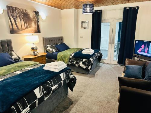 2 Betten in einem Zimmer mit einem TV und einem Sofa in der Unterkunft Modern 2 Bedroom Apt Derby City in Derby