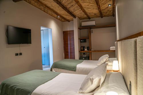 a hotel room with two beds and a flat screen tv at Las Terrazas Hotel Boutique in Tilcara