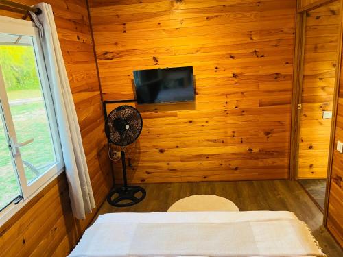 a bedroom with a wooden wall with a fan and a television at Bungalow TEIPO in Teavaro
