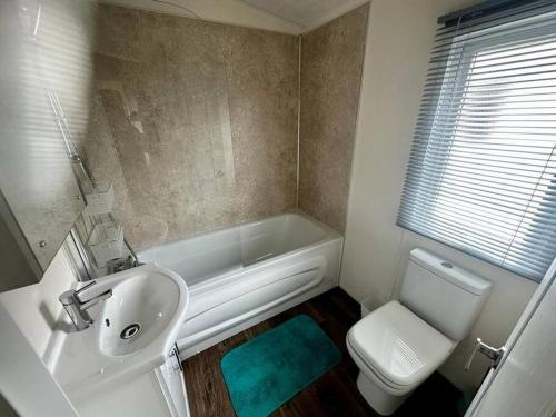 a bathroom with a sink and a tub and a toilet at 6 berth luxury caravan, Lyons Winkups Holiday Park in Kinmel Bay