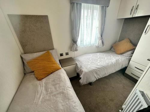 a small bedroom with two beds and a window at 6 berth luxury caravan, Lyons Winkups Holiday Park in Kinmel Bay