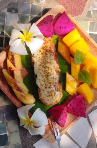 a plate of food with fish and fruit on a table at Harry's Ocean House Watukarung Homestay in Kalak