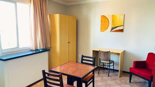 a room with a table and a red chair and a table and a desk at Hotel Atlantico Macaé By Inn House in Macaé