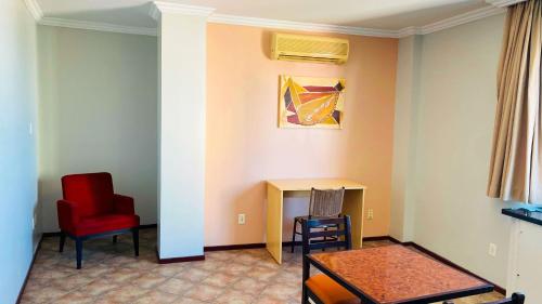 a living room with a red chair and a table at Hotel Atlantico Macaé By Inn House in Macaé