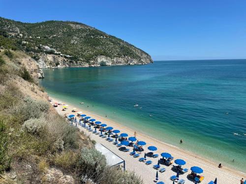 - une plage avec des parasols bleus et l'océan dans l'établissement Dimora Garibaldi, à Peschici