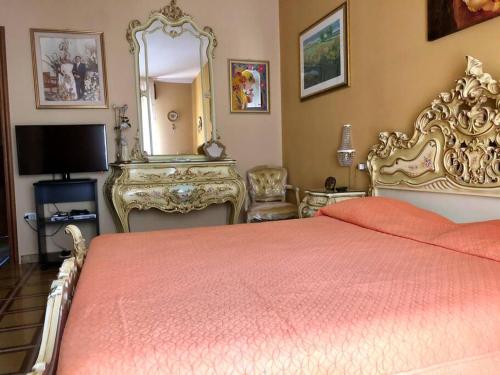 1 dormitorio con cama, espejo y TV en Appartamento nel cuore della Basilicata, en Ruvo del Monte