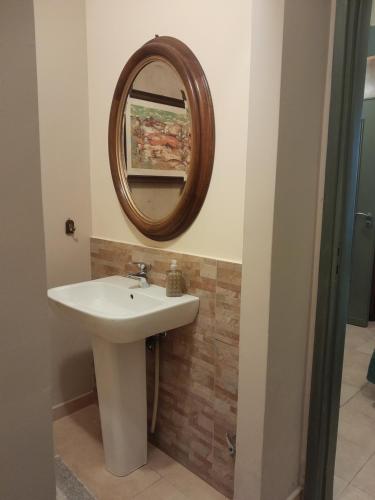ein Bad mit einem Waschbecken und einem Wandspiegel in der Unterkunft Casa Castelli Appartamento vacanza in Bagheria