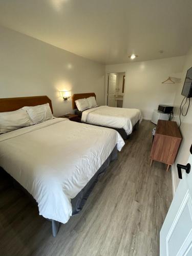 1 dormitorio con 2 camas y mesa con TV en Lake View Inn Lake George en Lake George