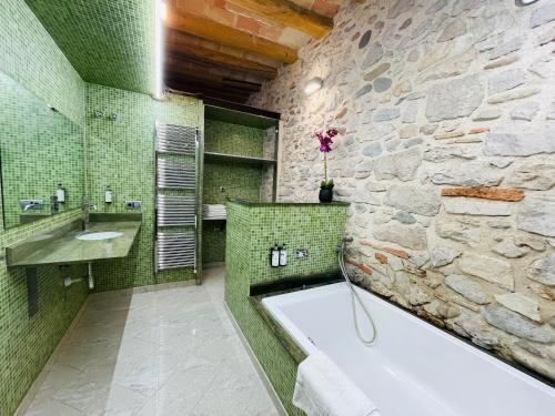 a bathroom with a stone wall and a tub and a sink at Cathedral Dreams in Girona