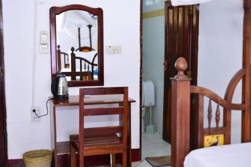 a bedroom with a mirror and a table and a chair at La Neisha Hotel Zanzibar in Stone Town