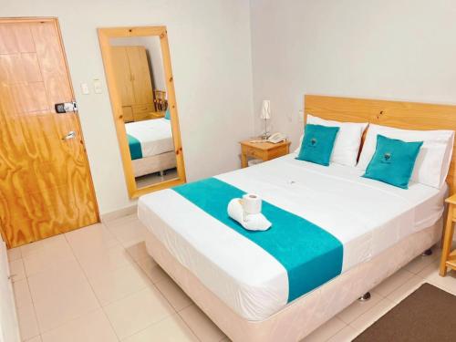 a bedroom with a large bed with blue pillows at Hotel Reycer in Piura