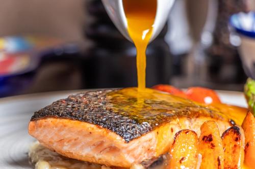 a plate with a piece of salmon with sauce on it at GHL Collection 93 in Bogotá